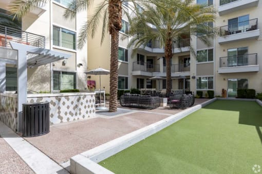 a courtyard with palm trees in front of an apartment building