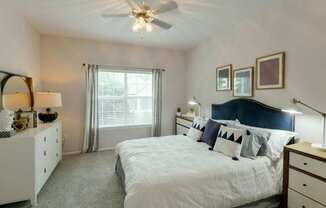 A bedroom with a bed, dresser, and window.