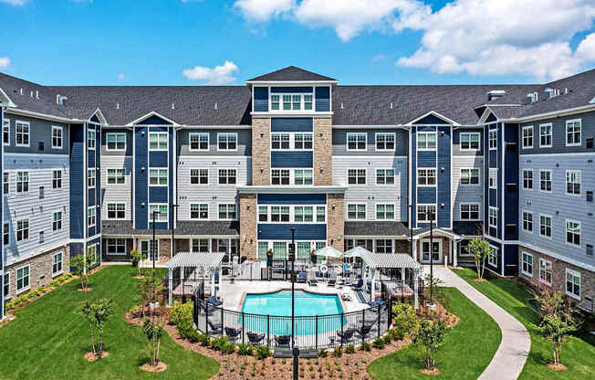 A large apartment complex with a pool in the middle of the courtyard.