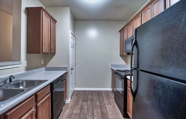 a kitchen with wood flooring and black appliances