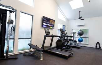 a gym with treadmills and weights and a tv