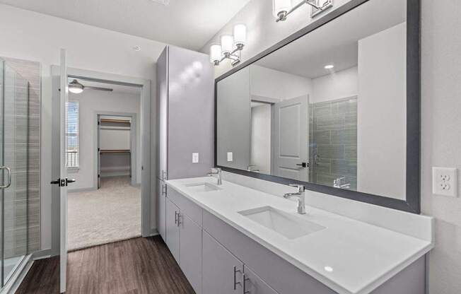 A bathroom with a sink, mirror, and a glass shower door.