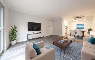 A living room with a large couch, a coffee table, and a flat-screen TV.