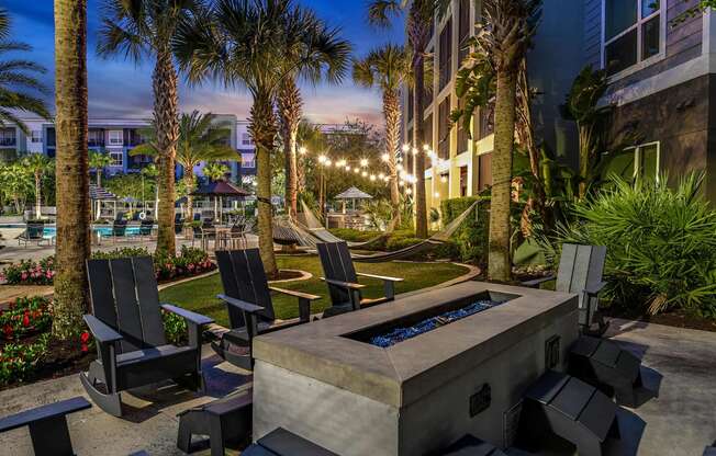 a patio with a fire pit and chairs at night