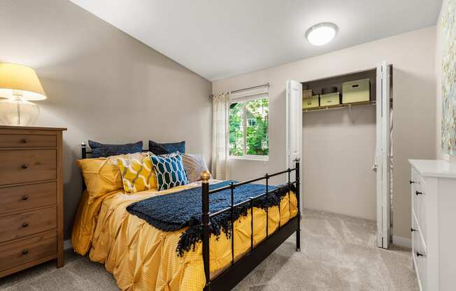 A bedroom with a yellow bedspread and blue pillows.