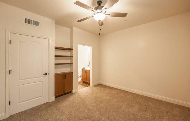 A room with a ceiling fan and carpeted floor.