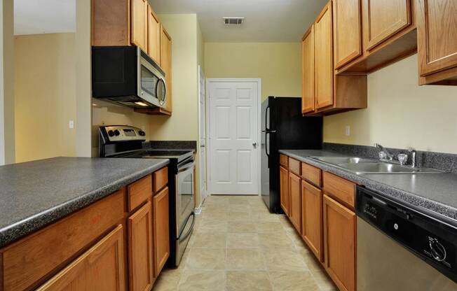 A kitchen with wooden cabinets and black appliances.