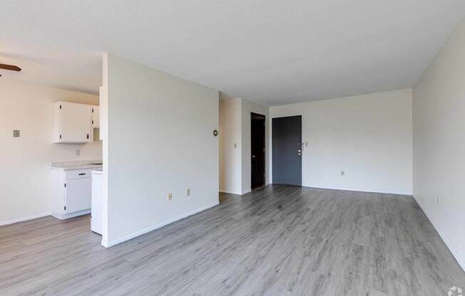 A spacious room with a kitchenette and a door leading to another room.