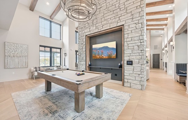 a pool table in a living room with a stone fireplace