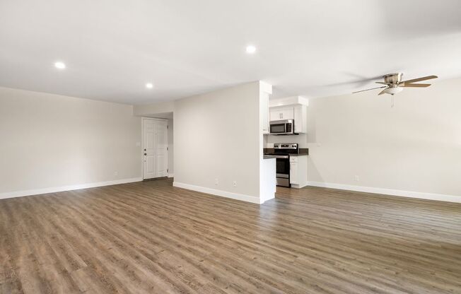 a living room and kitchen with wood flooring and a ceiling fan
