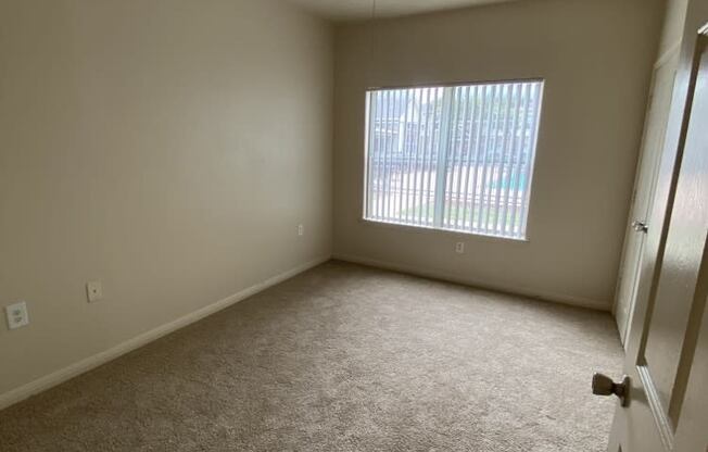 an empty room with a ceiling fan and a window