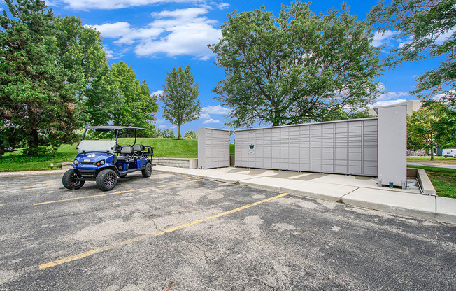 A blue golf cart is parked next to Amazon Hub package lockers at The Crossings Apartments in Grand Rapids, MI