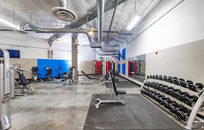 A gym with a variety of equipment including dumbbells and weight machines.