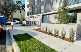 an empty sidewalk in front of an apartment building