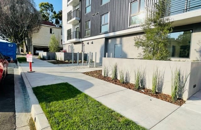 an empty sidewalk in front of an apartment building