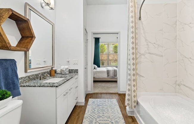A bathroom with a white tub and a marble wall.