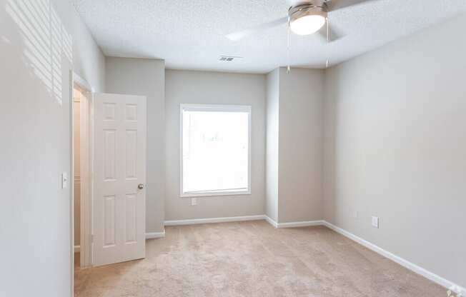 an empty room with a white door and a window