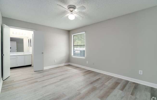 an empty living room with a ceiling fan and a window