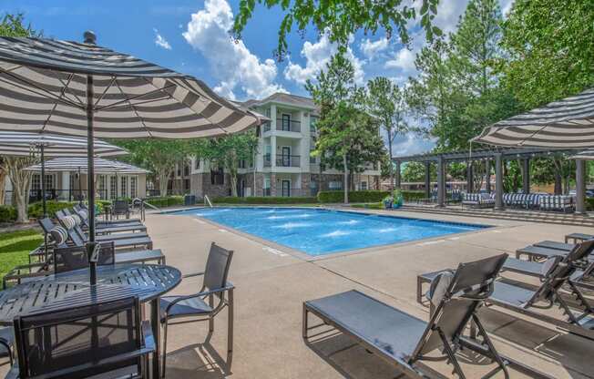 Affordable Houston Texas Apartments – Westchase Forest – Photo of our apartments offer a swimming pool with chairs and umbrellas