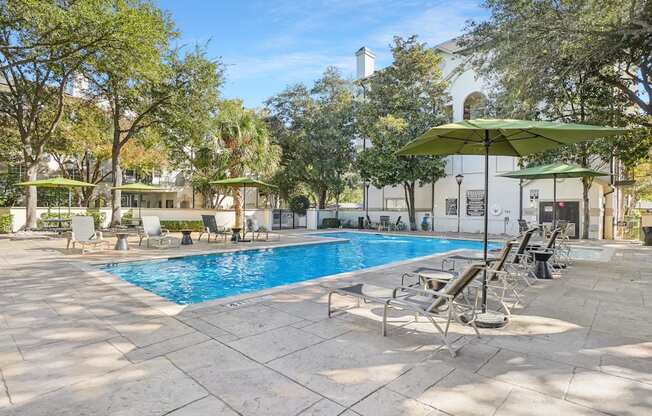 A pool surrounded by trees and chairs.