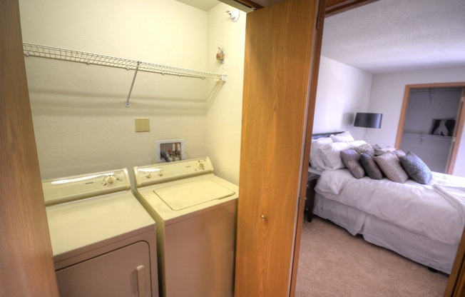 a bedroom with a washer and dryer next to a bed