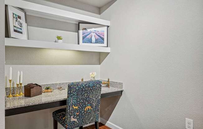 A chair with a colorful pattern sits in front of a counter with a small plant on it.