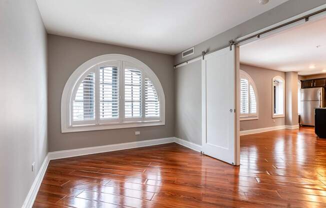 an empty living room with a large window and wooden floors