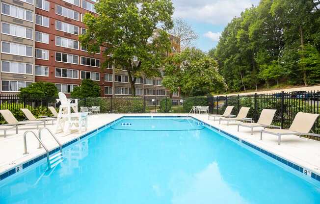 A large swimming pool with lounge chairs and a building in the background.