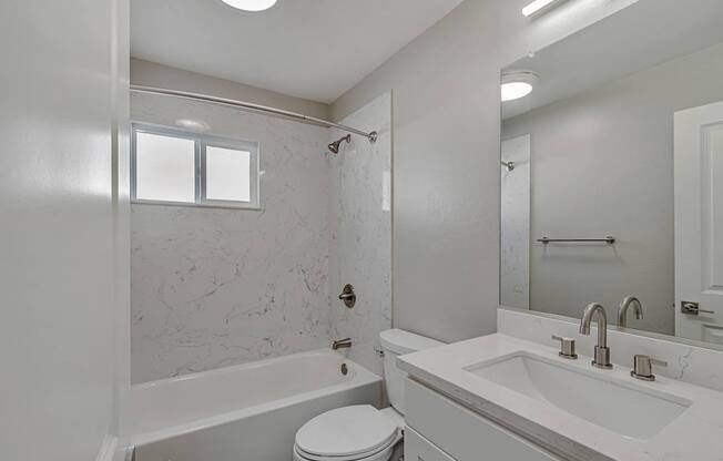 A white bathroom with a tub, toilet, and sink.