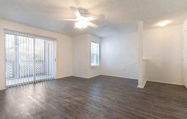 A room with a ceiling fan and a window with blinds.