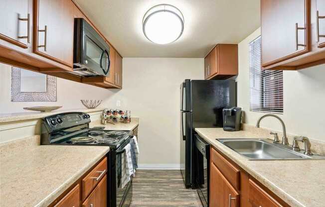 A kitchen with black appliances and wooden cabinets.