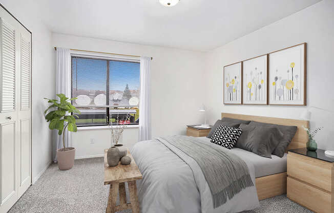 A bedroom with a large bed, a window with a view, and a potted plant.