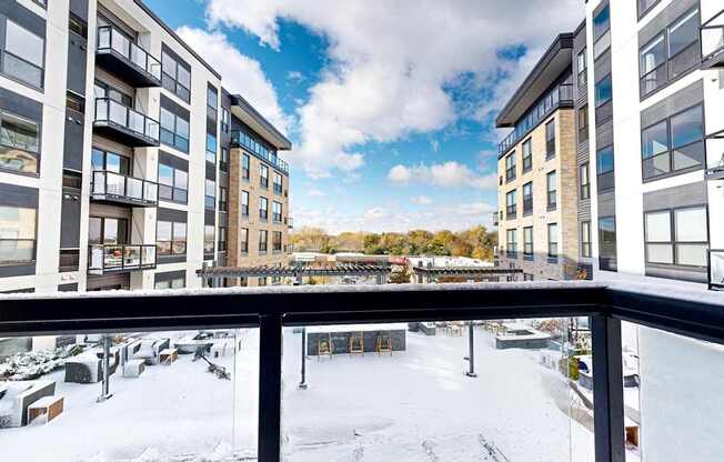 A view from a balcony of a snow-covered courtyard between two buildings.