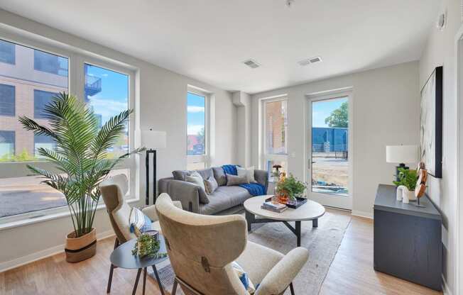a living room with a couch table and chairs and a large window