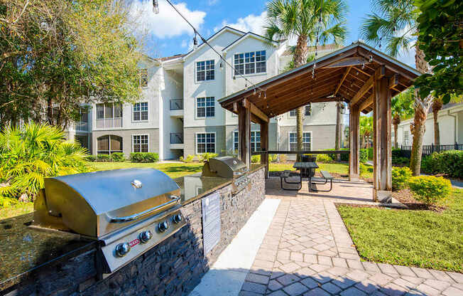 a patio with a grill and a picnic area with a building in the background