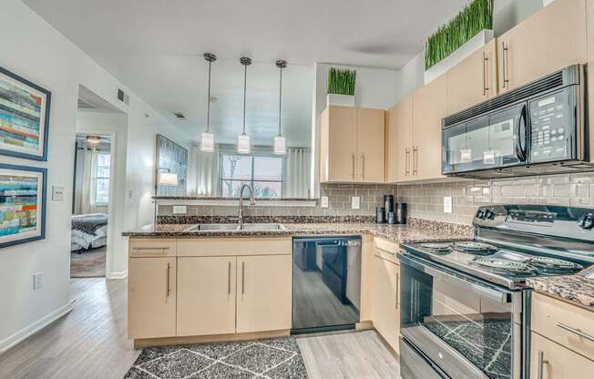 A kitchen with a black stove top oven and a black and white rug on the floor.