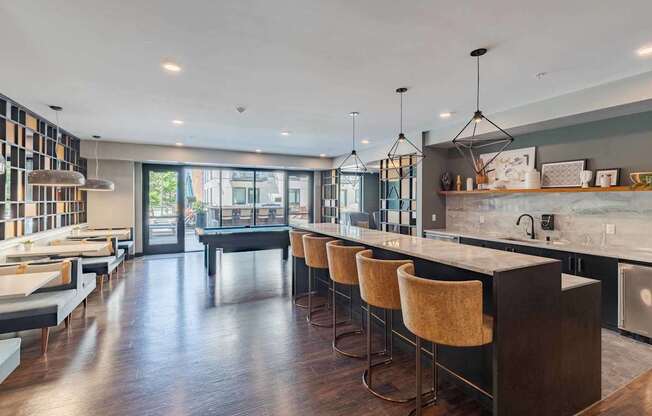 A modern kitchen with a long bar and chairs.