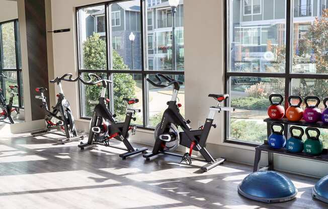a gym with exercise bikes and weights in front of a window