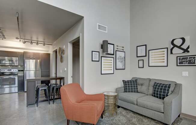 a living room with a couch chair and a dining room table in the background