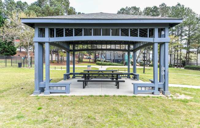 a pavilion with a picnic table and benches in a park