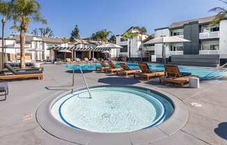 A round swimming pool surrounded by sun loungers and umbrellas at Verandas Apartments, California, 91791
