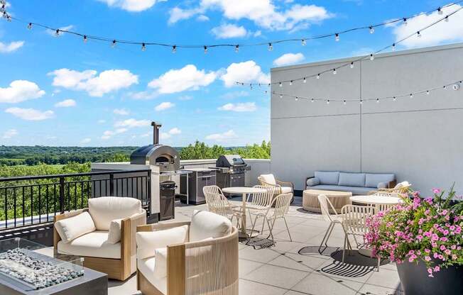A balcony with chairs, tables, and a grill overlooking a scenic view.