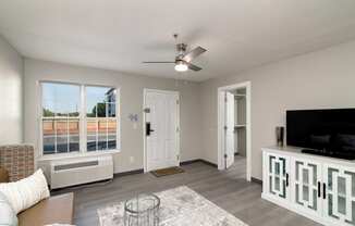 an open living room with a large window and a ceiling fan