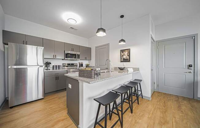 A kitchen with a refrigerator, stove, and bar stools.