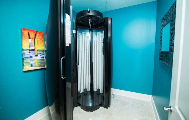 A black and silver water heater in a room with blue walls.