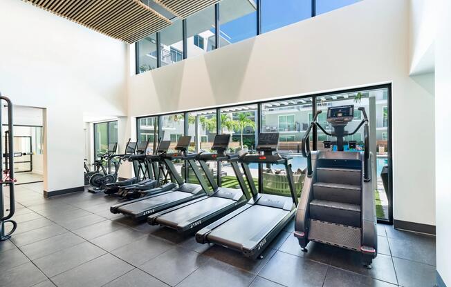 The fitness center features premium cardio equipment, expansive windows, and an open-concept design that supports a variety of workout routines.