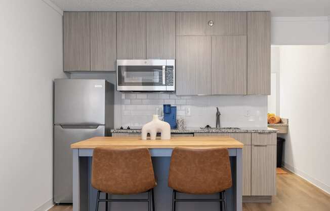 a kitchen with stainless steel appliances and a island with two chairs at The Teale Navy Yard, North Charleston, SC, 29405