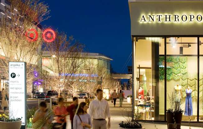 people walking down a busy city street in front of a shopping mall