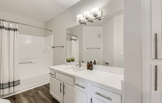 a bathroom with white cabinetry and a white shower curtain