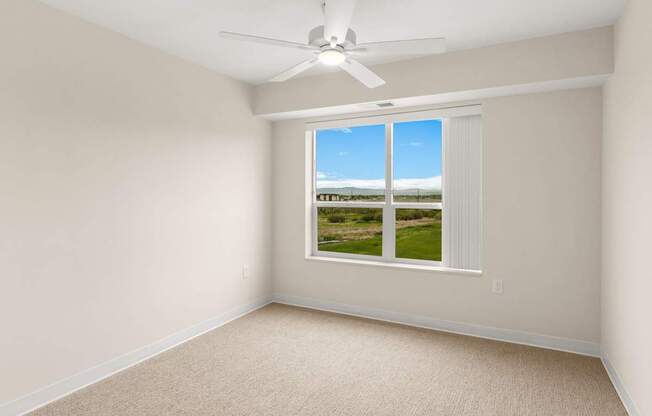 A room with a window overlooking a field.